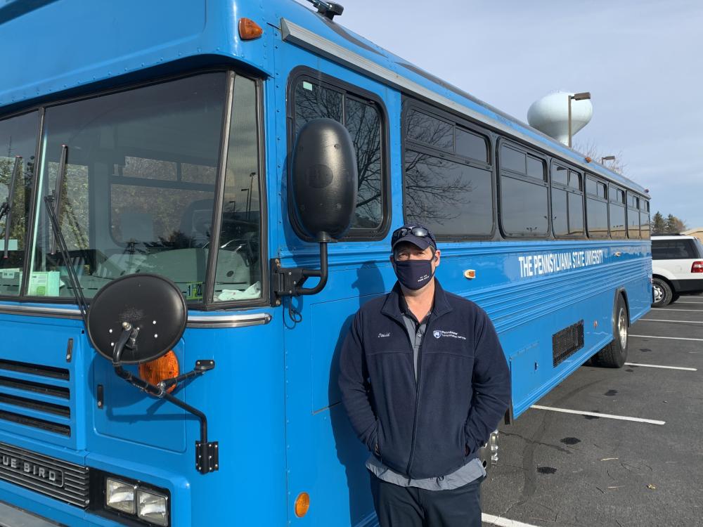 一名司机站在mg游戏平台蓝色巴士隔离班车旁 