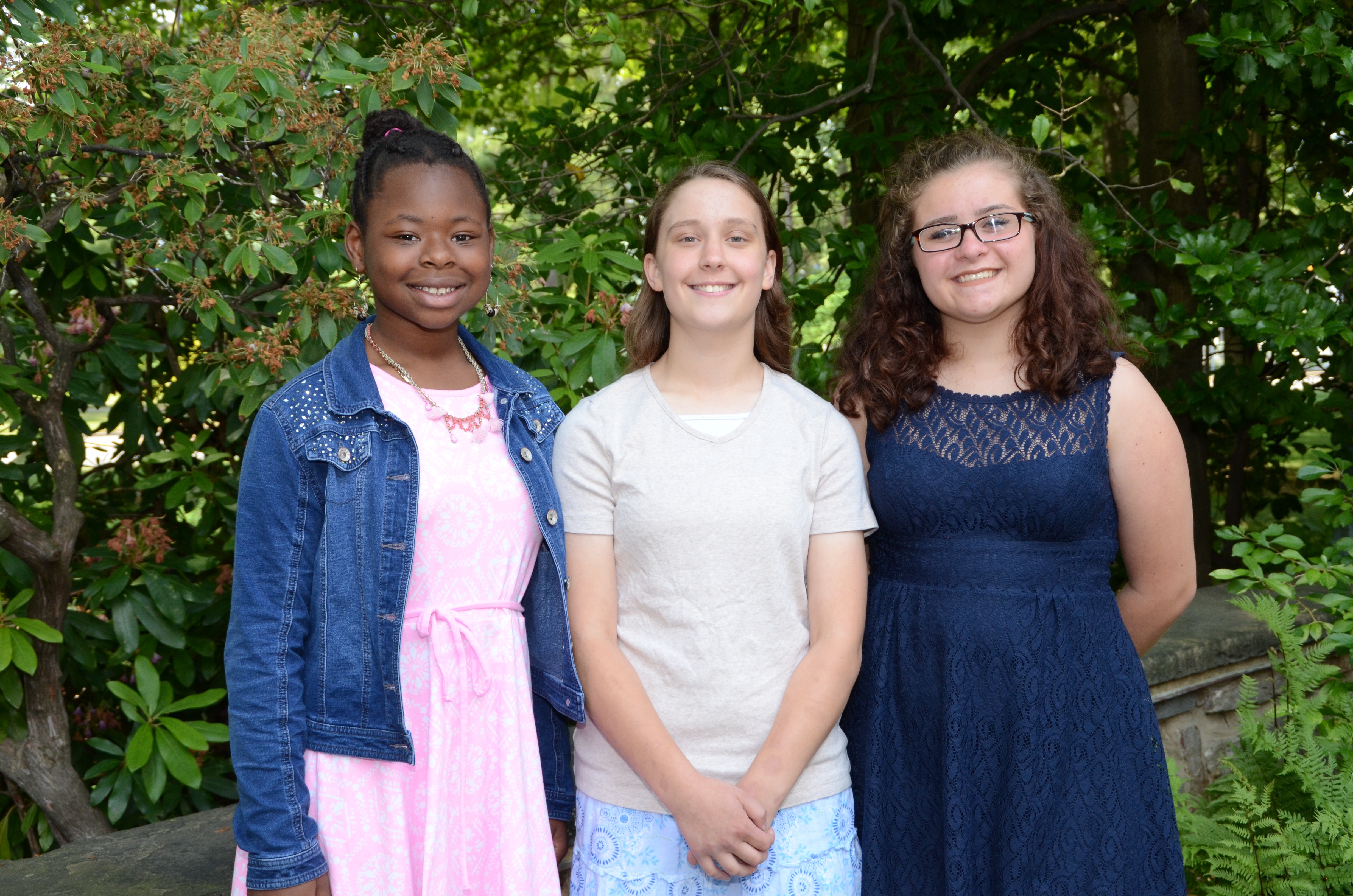 2016 Letters about Literature winners; outdoor photo of three female students standing in front of green foliage