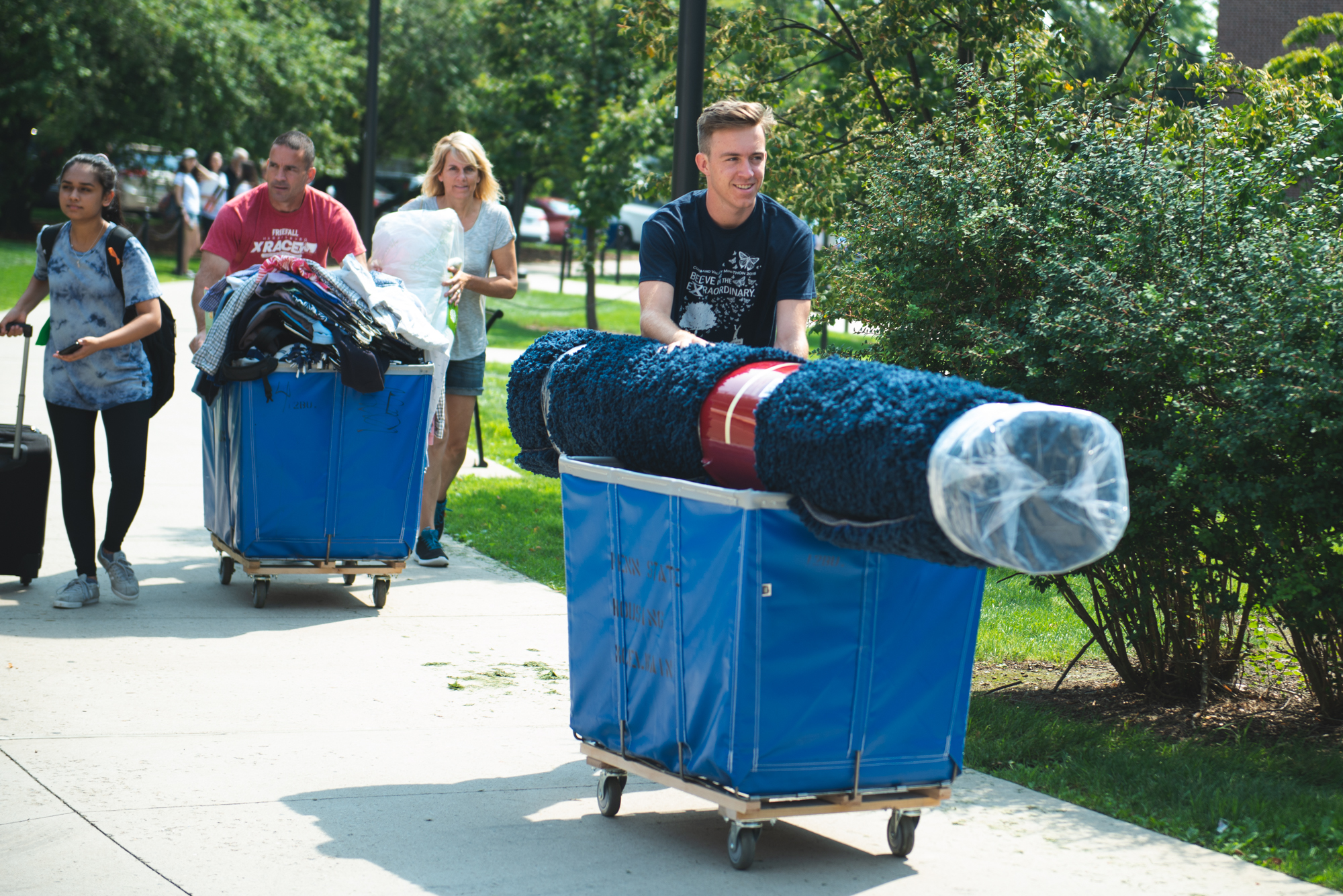 Students and parents pushing carts down the sidewalk at Penn State's University Park campus. 