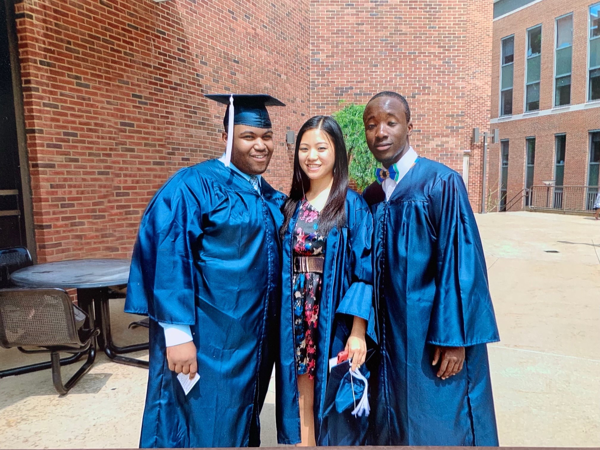 Three graduates in wearing blue commencement gowns