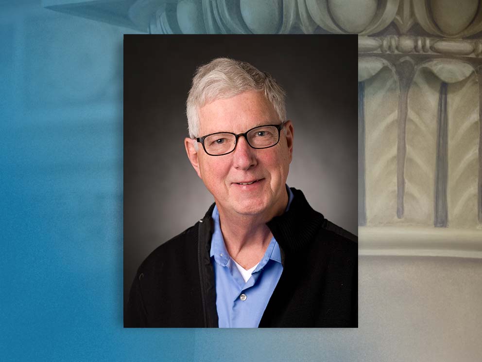 head and shoulders portrait photo of a man in office attire with glasses