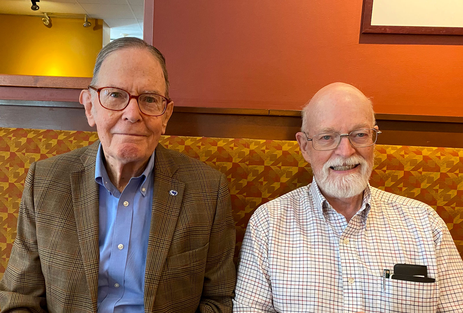 two men sit at restaurant booth