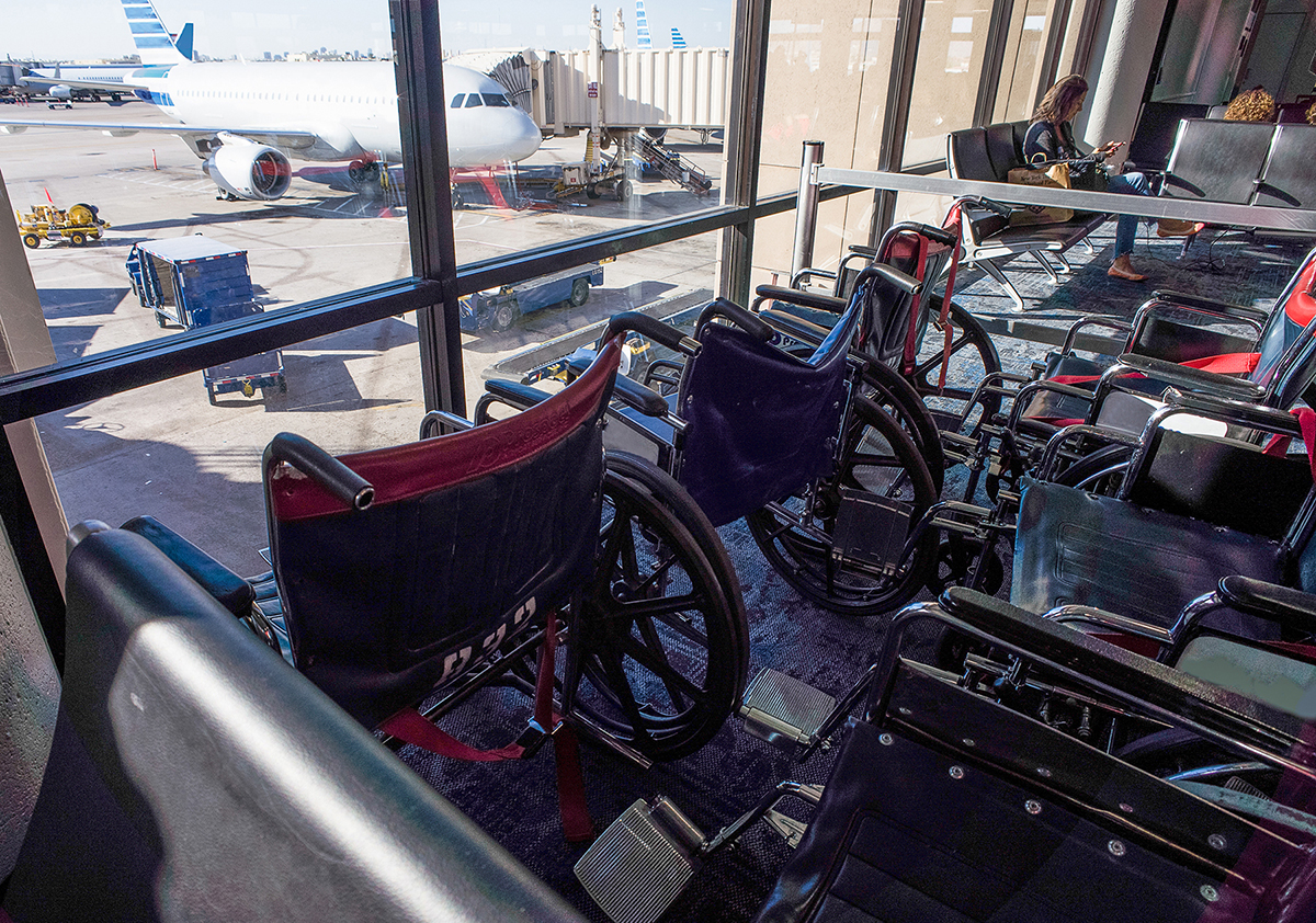 image of wheelchairs sitting in a airport terminal overlooking an airplane 