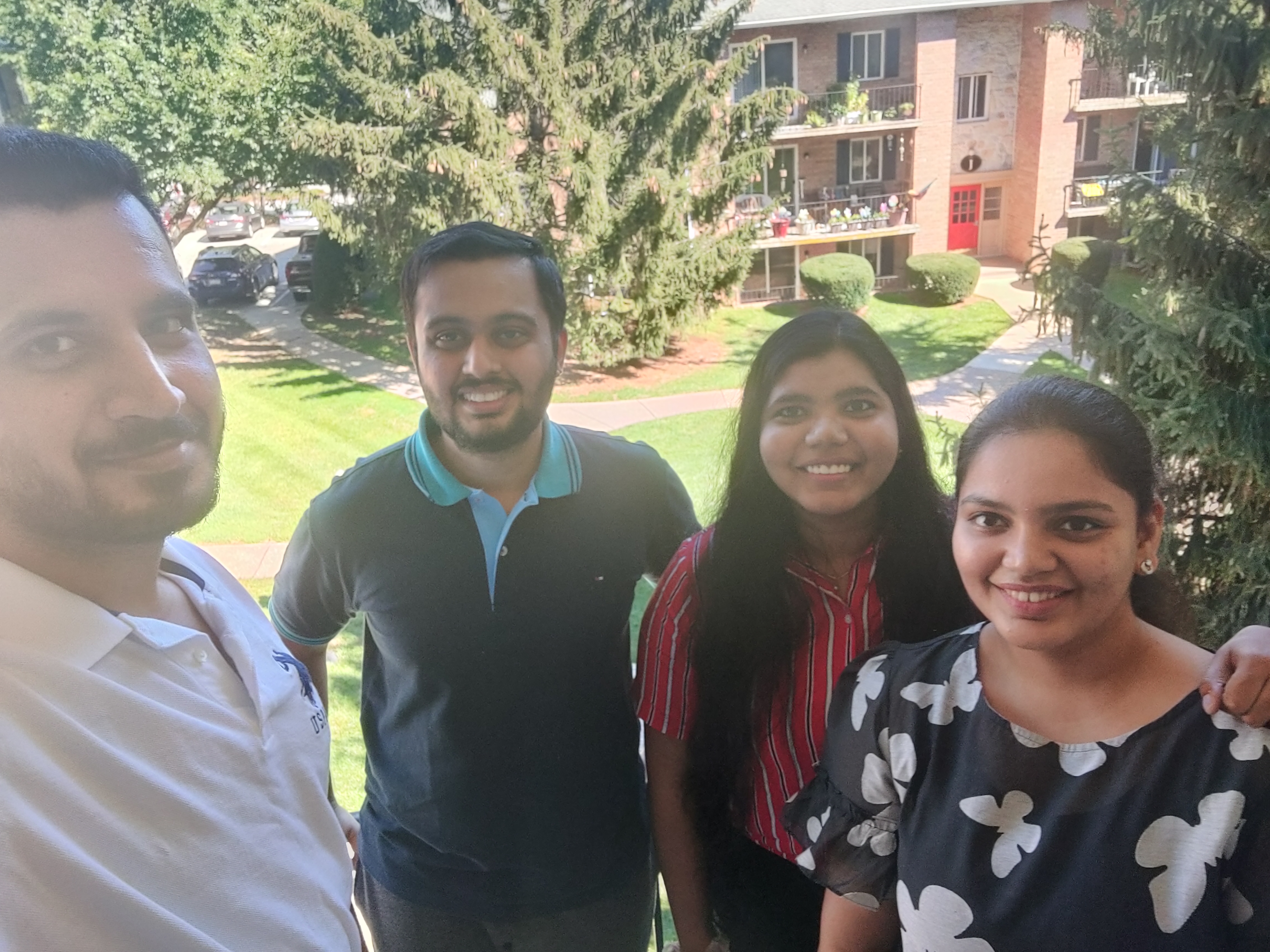 Four students smiling and standing outside