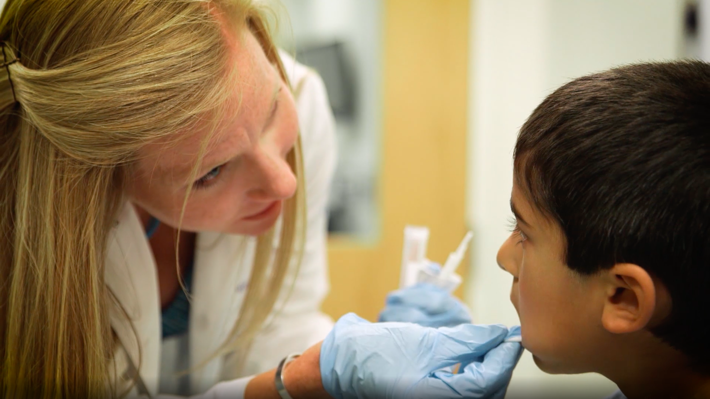 nurse takes a cheek swab from a child