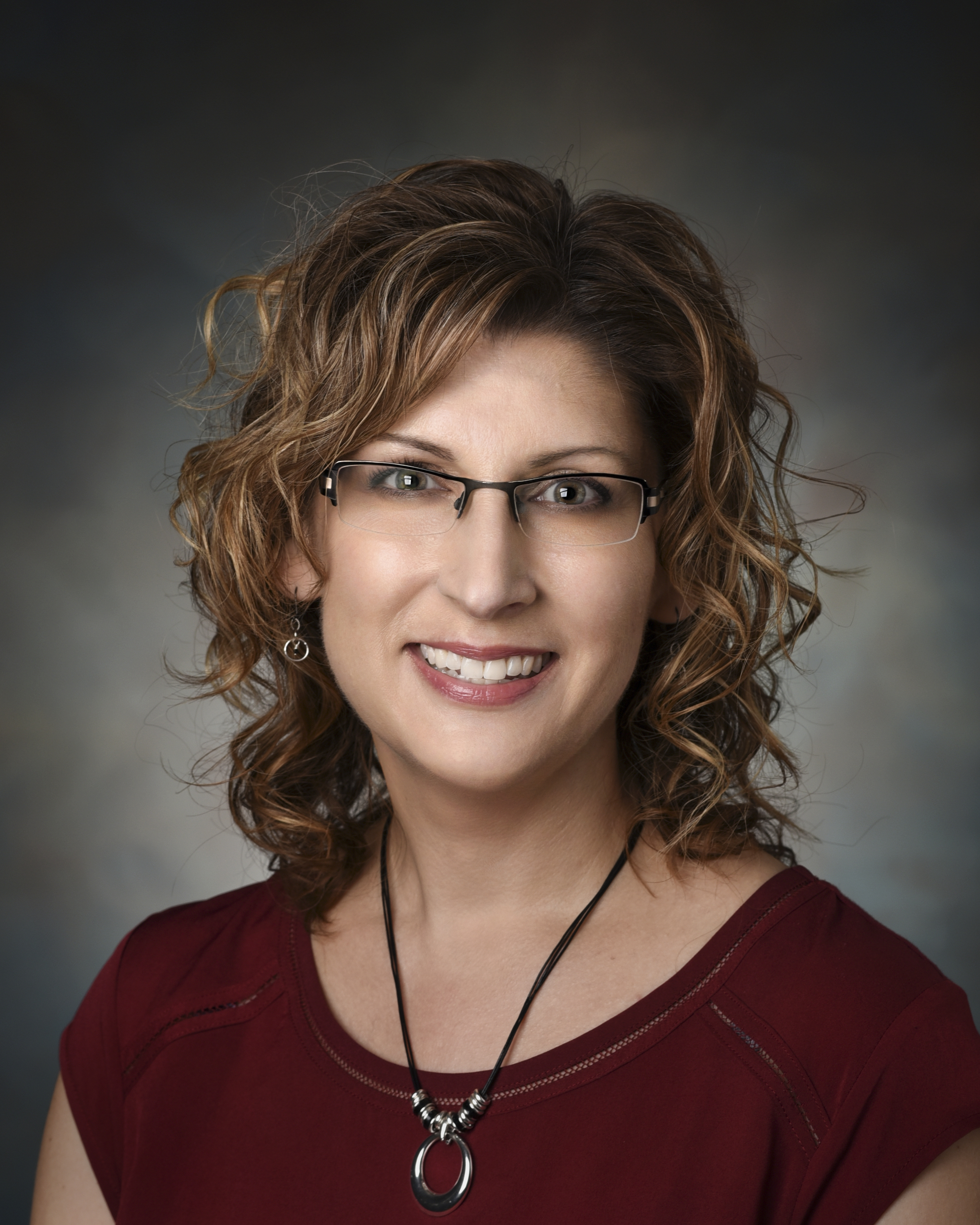 A woman in glasses smiles for her headshot