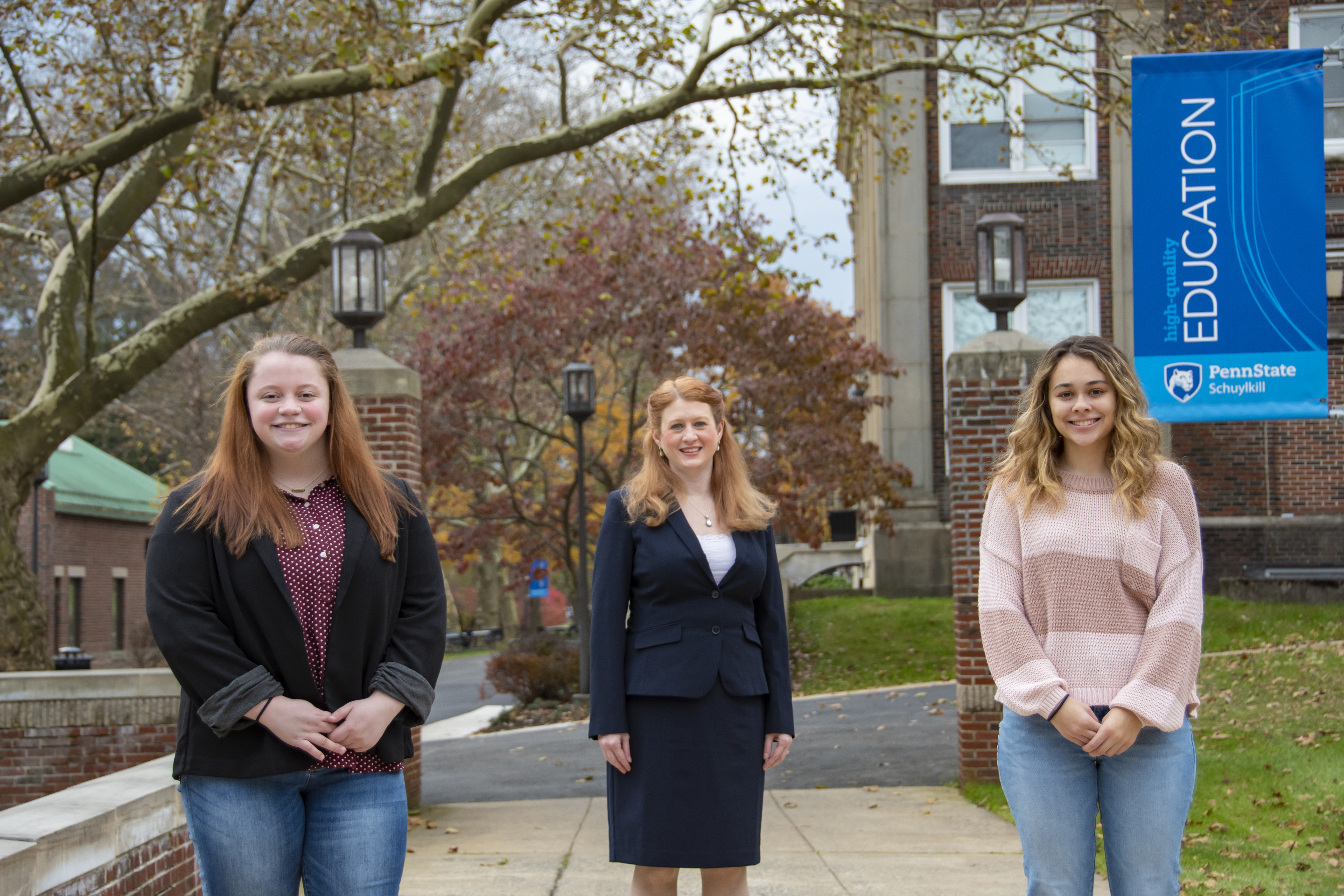 An image of two female students and professor with campus mall walk behind them.