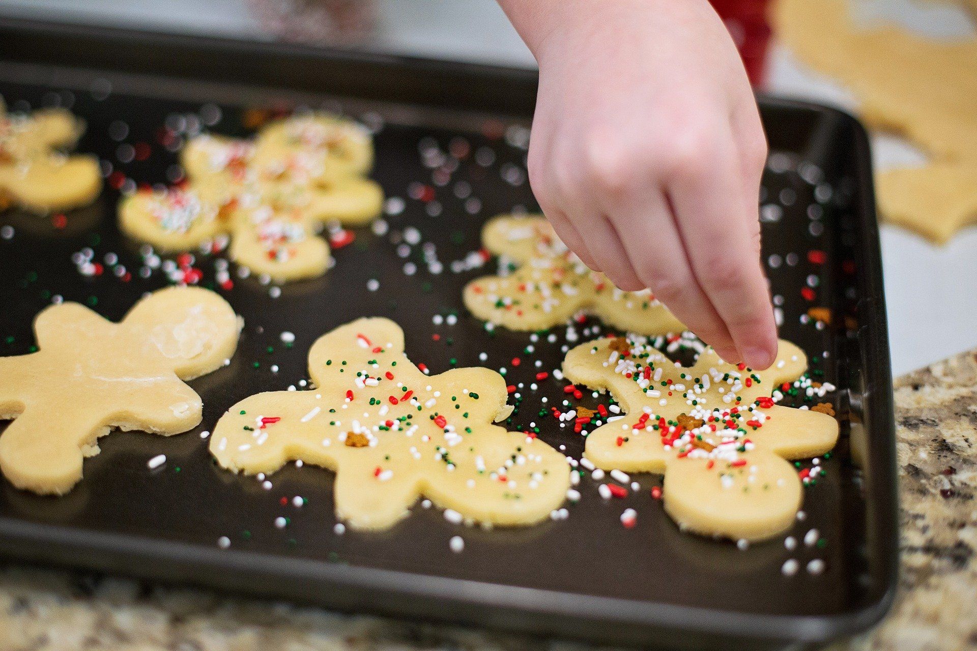 Baker putting sprinkles on Christmas cookies