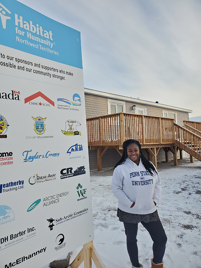 Miriam Pallard standing next to a Habitat for Humanity sign