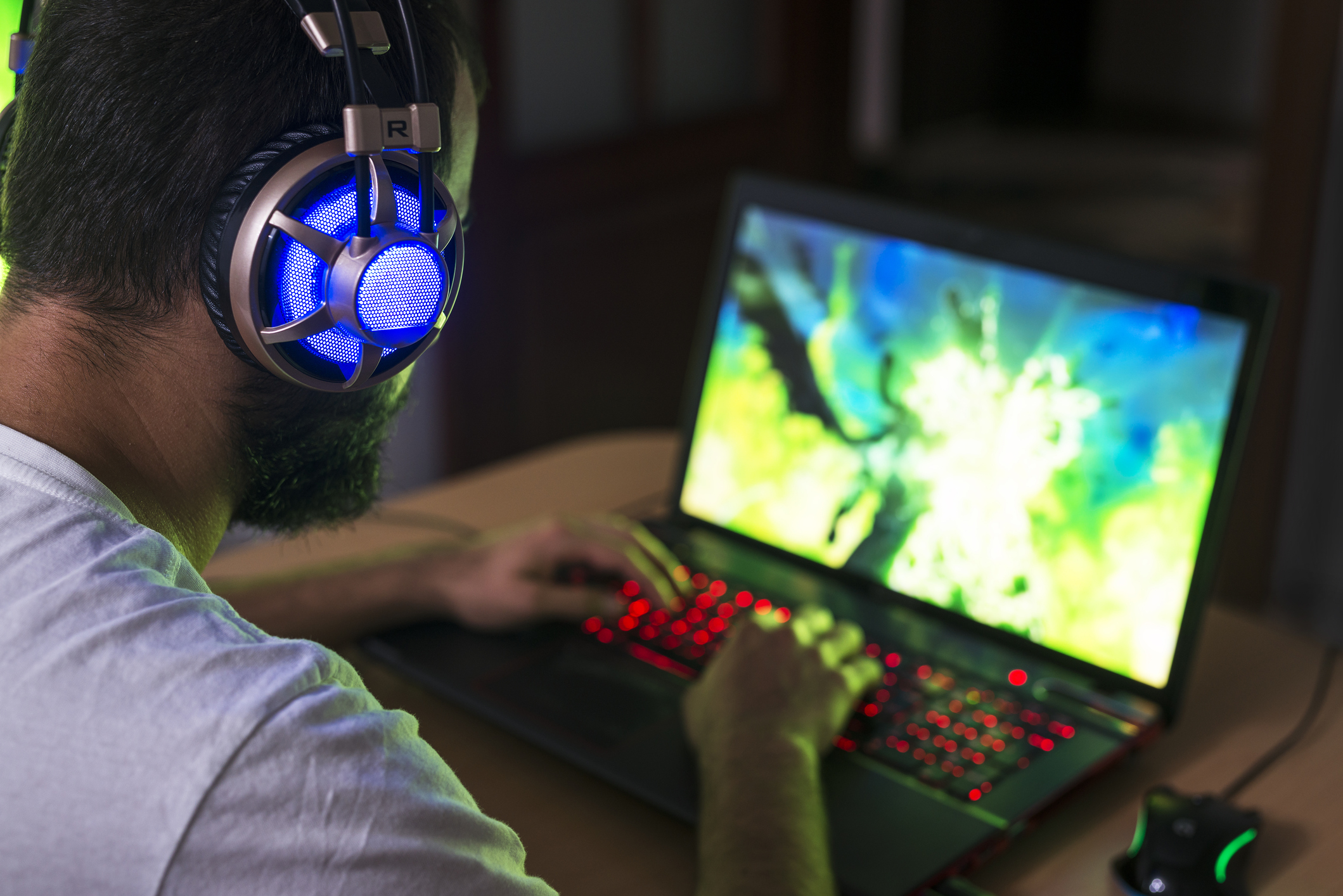 Photo of a gamer wearing headphones and sitting at a desktop computer playing a game