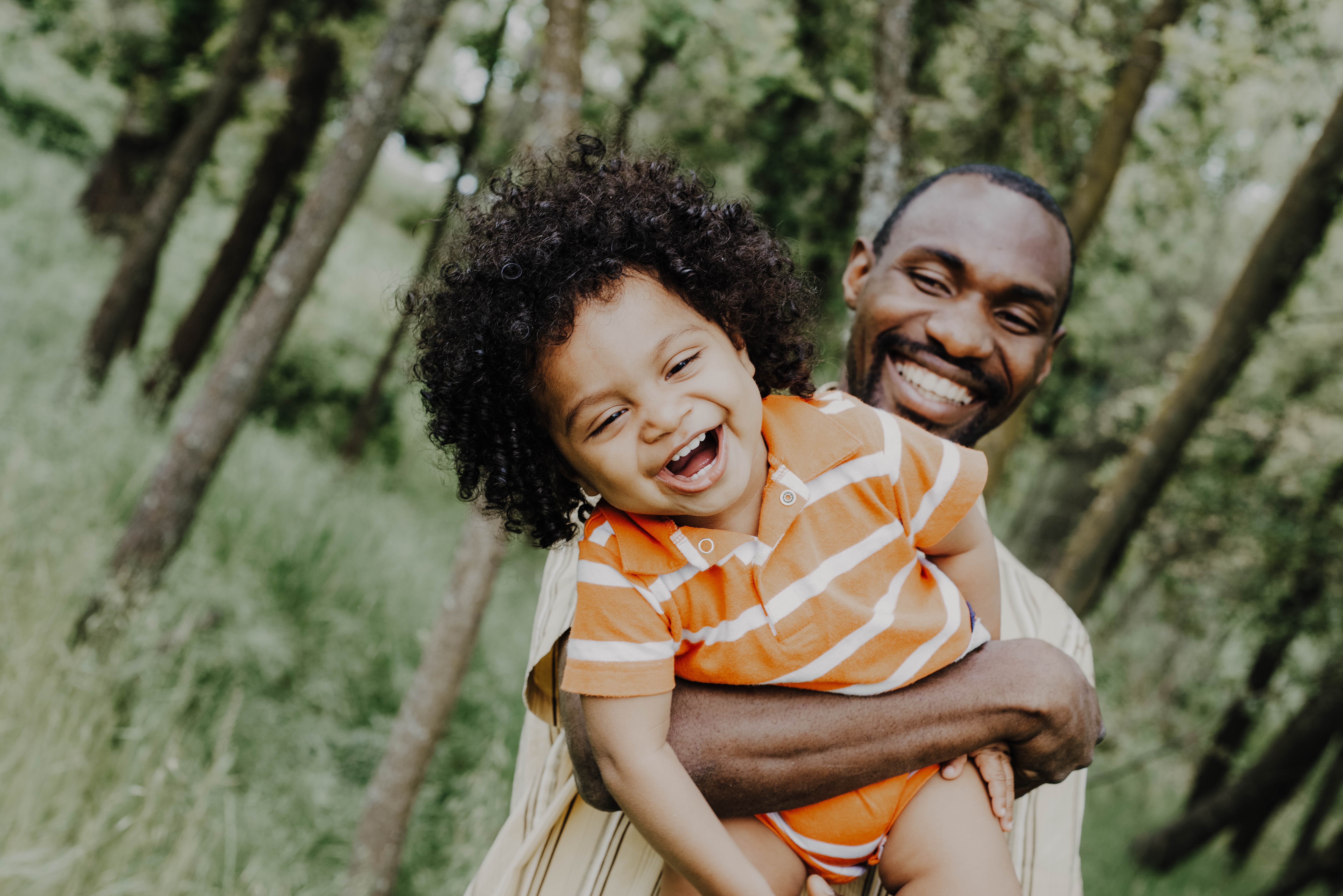 A Black man holding a grinning toddler