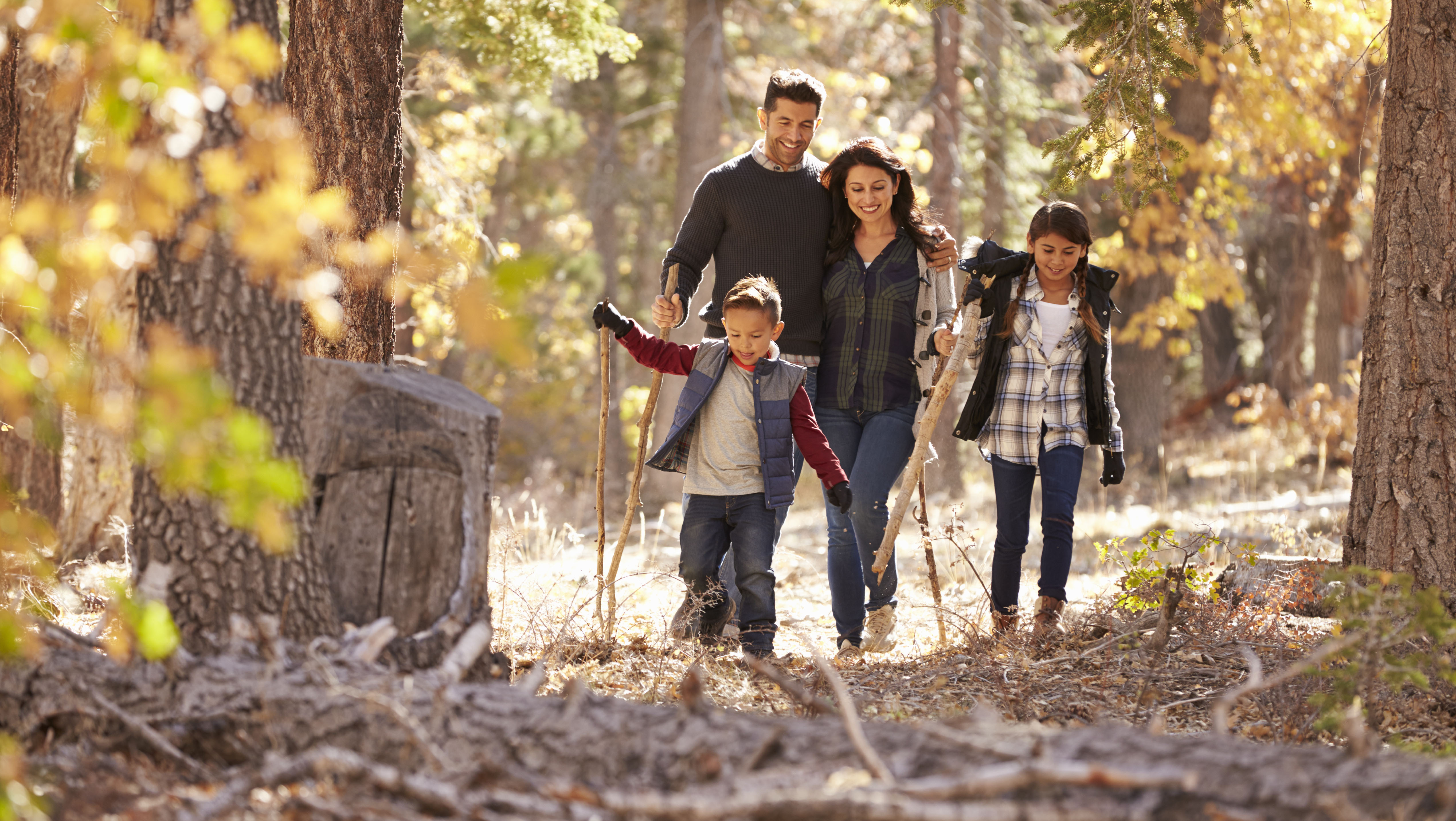 Mother, father, and two children walking in the woods in the autumn