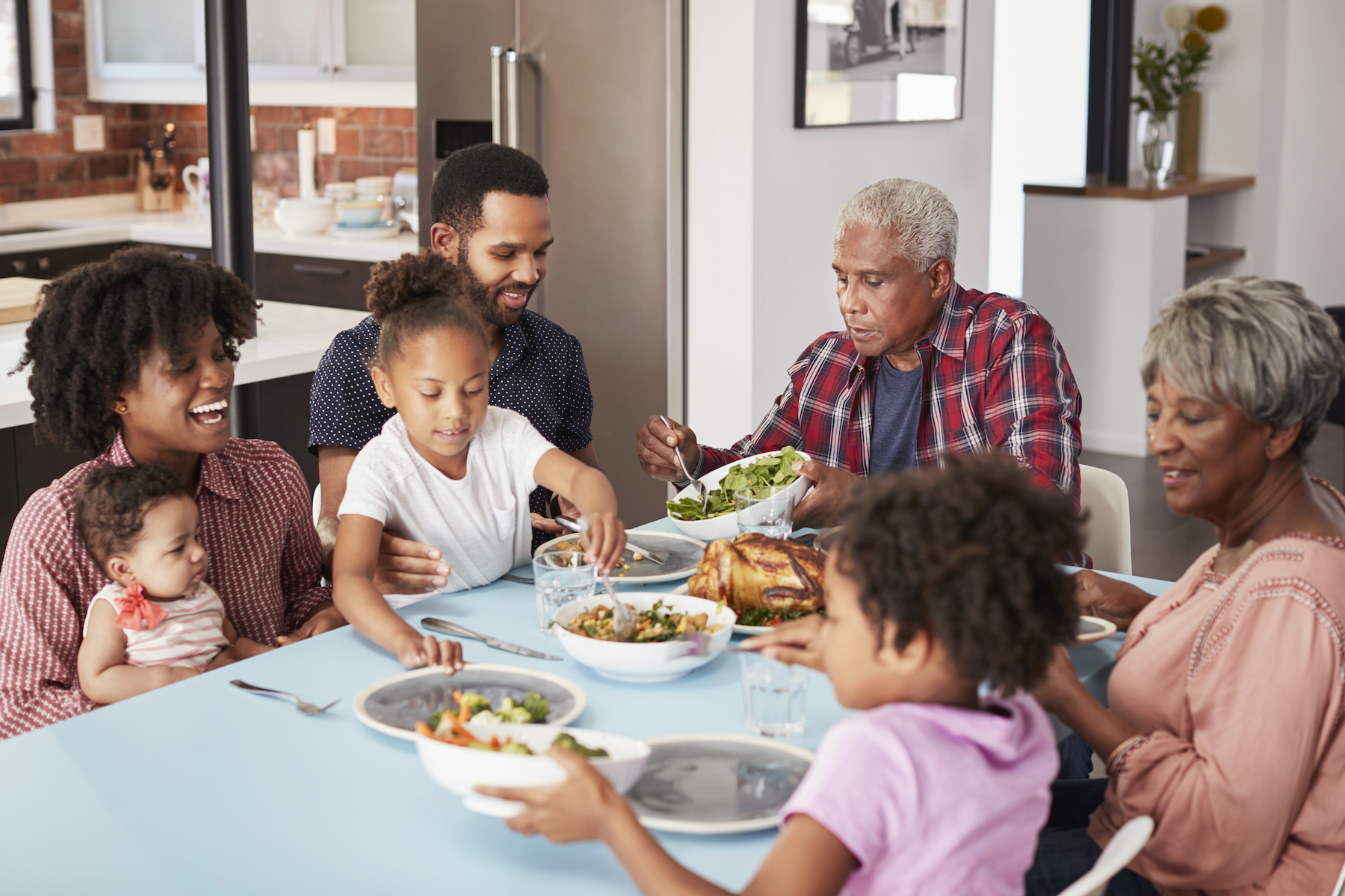 Multi-Generation Family Enjoying Meal Around Table At Home