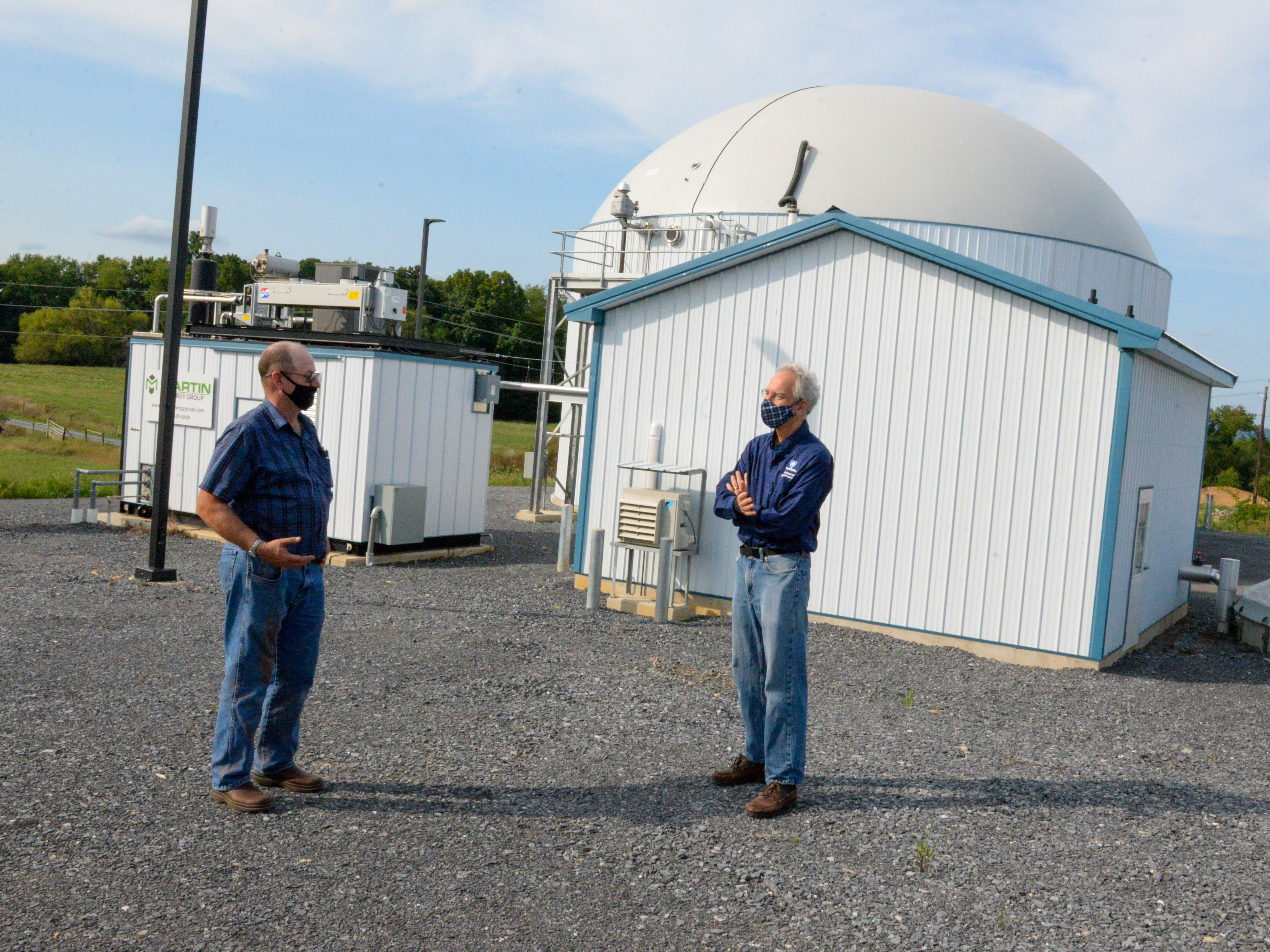 Two men standing outside next to an on-farm anaerobic digester.