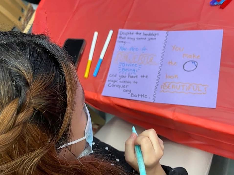 Health and Human Development student writes a message in a Valentine's card that will be delivered to hospice patients