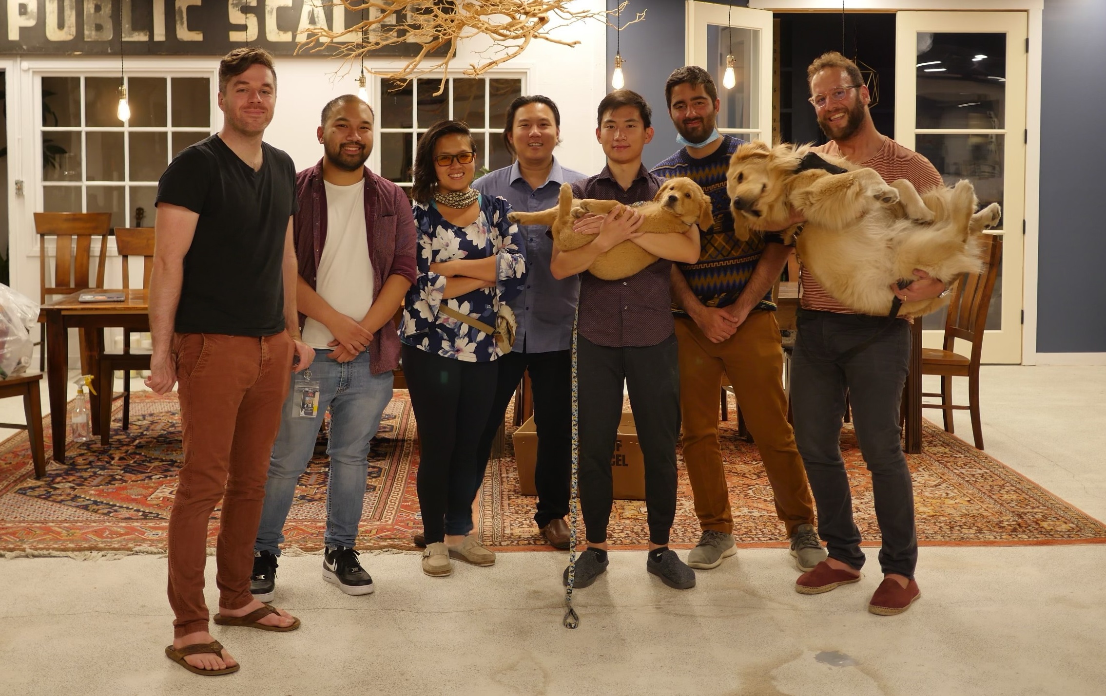 Thanh Le and fellow Moichor staff members with two golden retrievers.