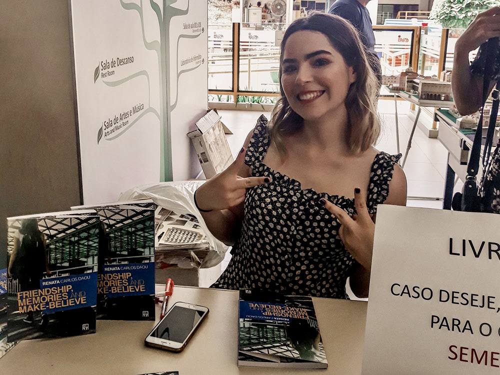 Renata Carlos Daou smiles while sitting at a table with books