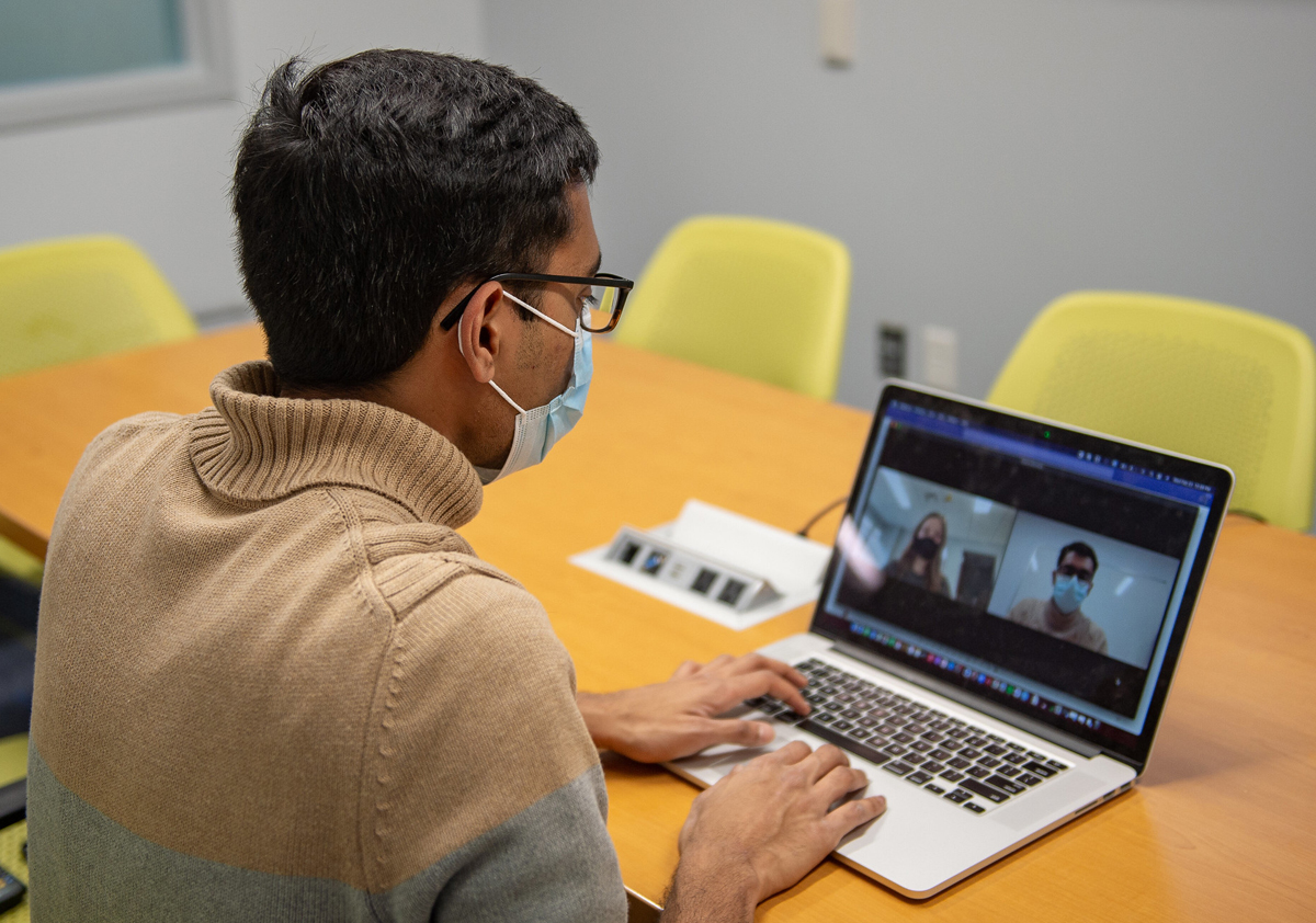 Researcher looking at a computer screen where a virtual meeting is taking place.