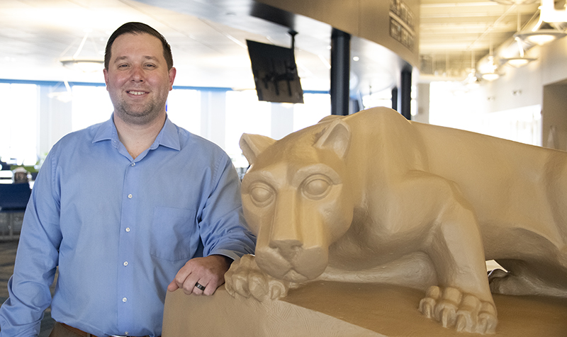 Alumnus Steve Strange poses beside the Community Center lion shrine