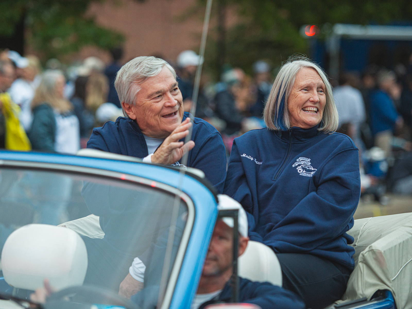 Penn State President Eric Barron waves to the crowd with wife Molly while sitting in a blue convertible during the 2021 Homecoming parade. 