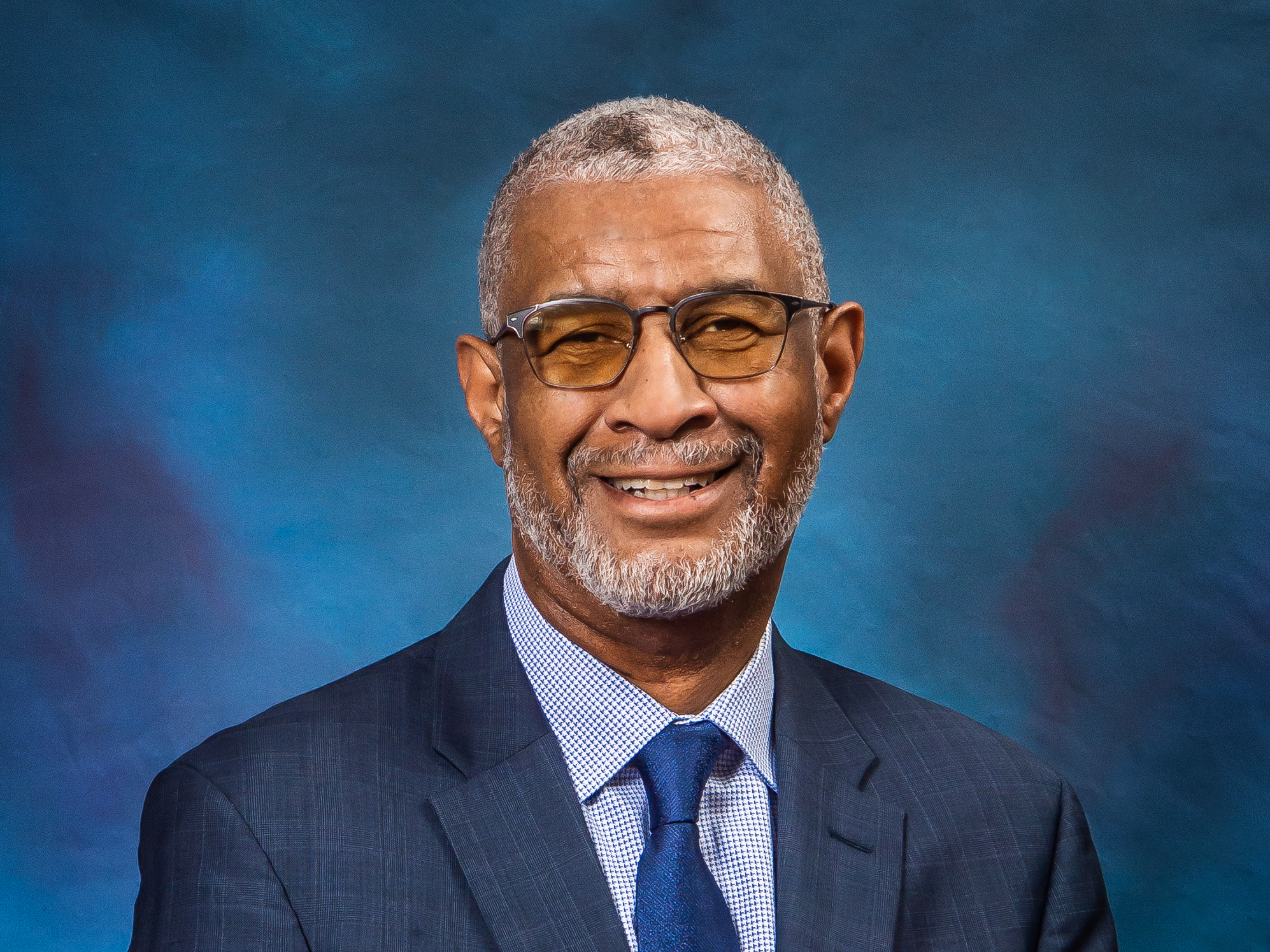 A headshot of Penn State Berks Chancellor George Grant Jr. wearing a blue suit against a blue background.