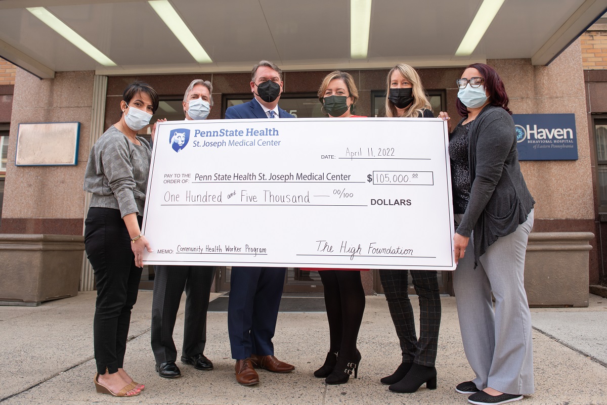 Six people pose with an oversized check in front of a building. The check, in the amount of $105,000, is from the High Foundation and made payable to Penn State Health St. Joseph Medical Center.