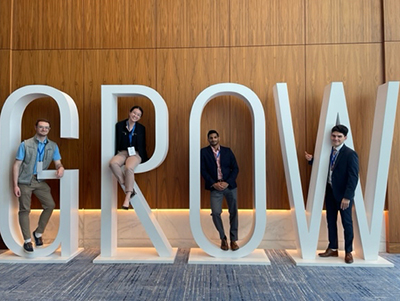 A photo of four students standing or sitting in the letters G R O W.