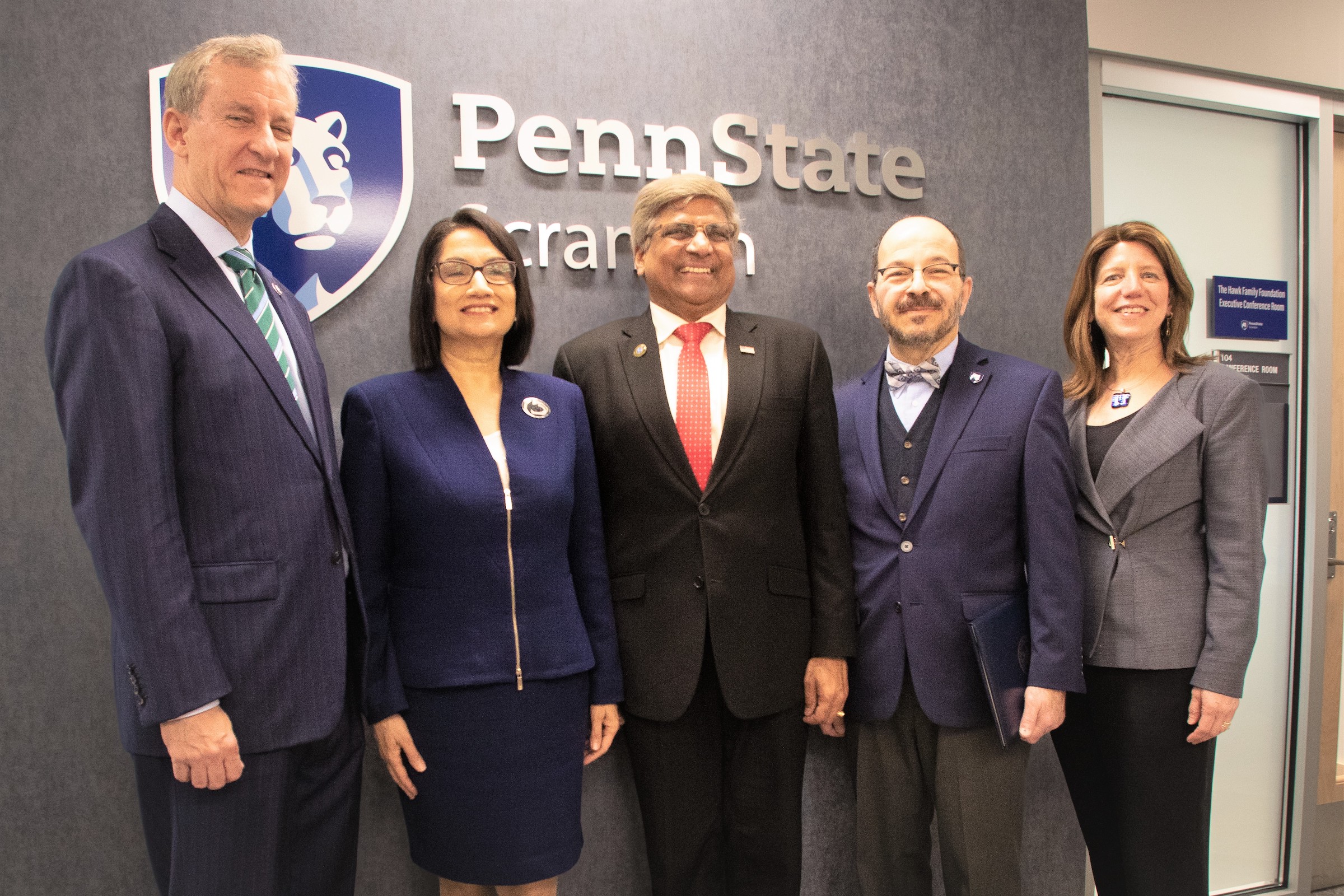 group of PSU officials and special guests posing for a photo in front of Penn State wall