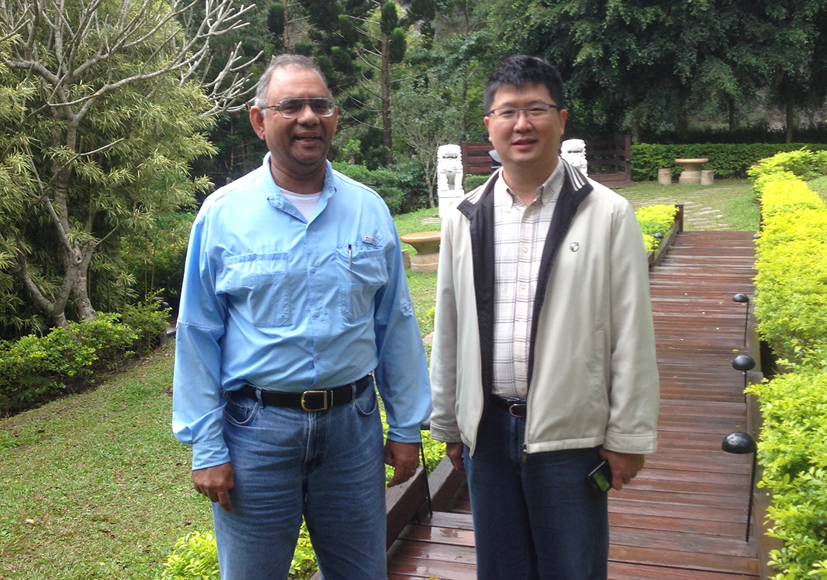 Two men stand together in a park. 