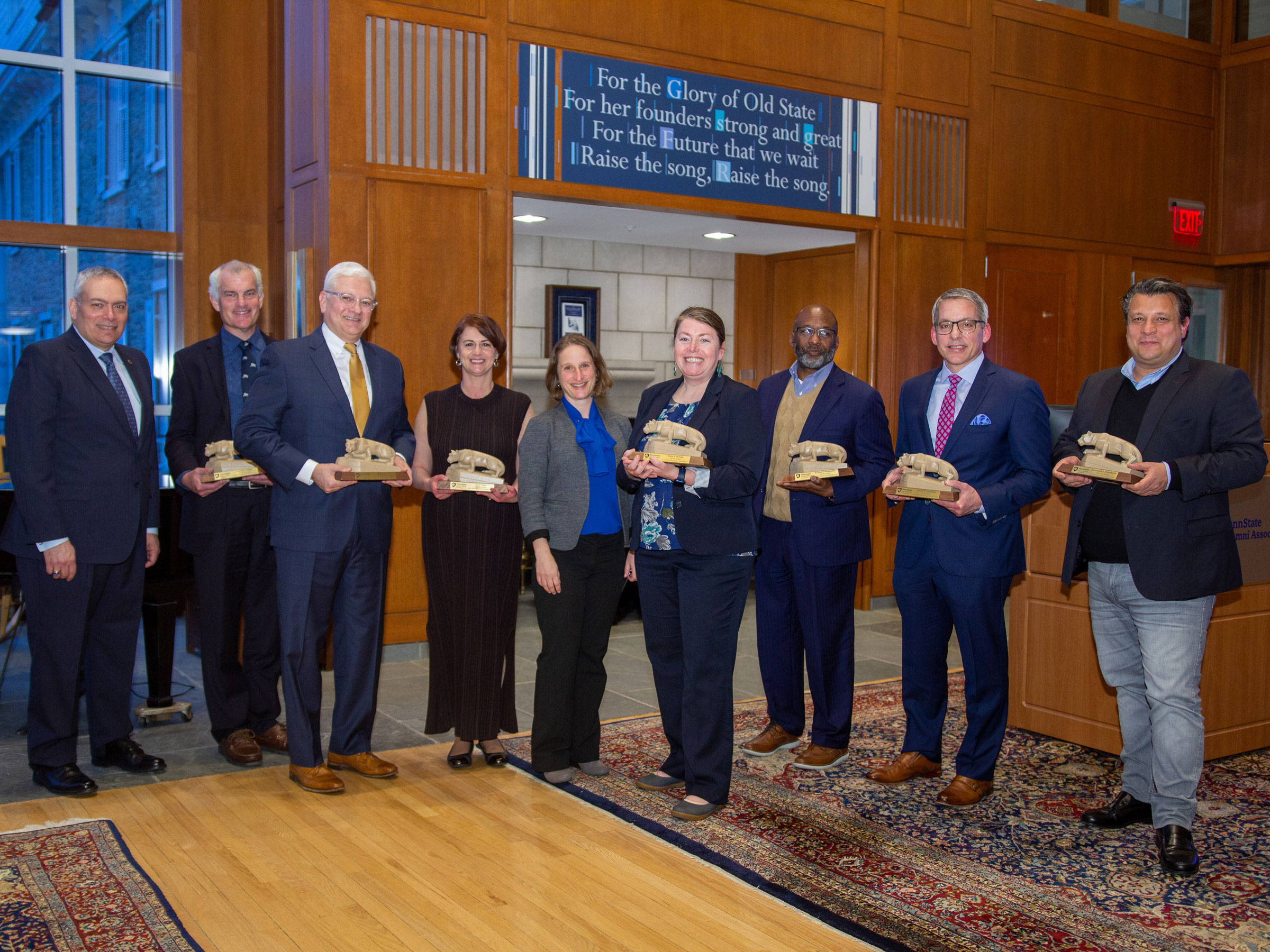 alumni award recipients hold statues next to Dean Langkilde