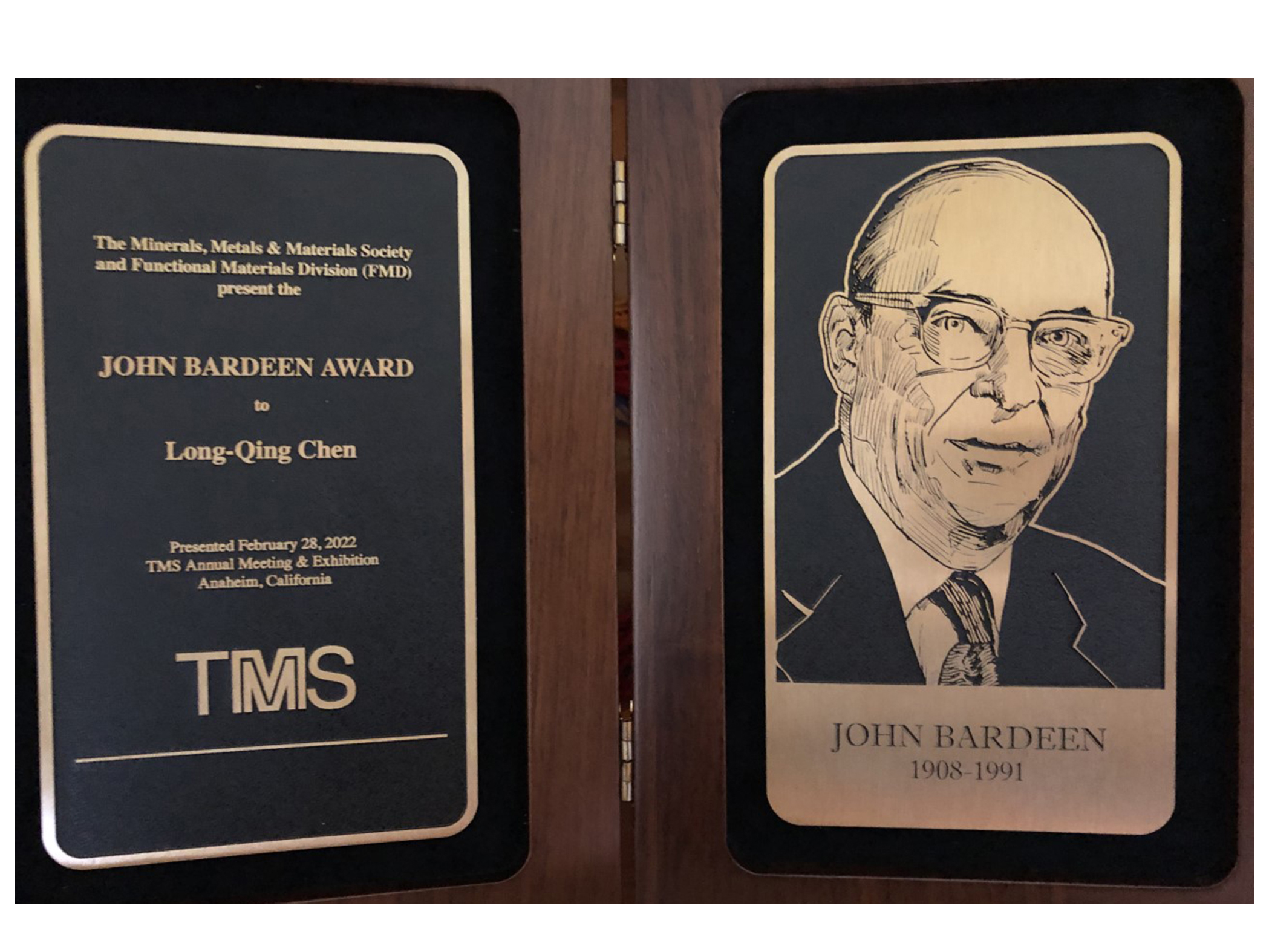 A brown and gold award with John Bardeen's portrait etched on on side and text on the other side