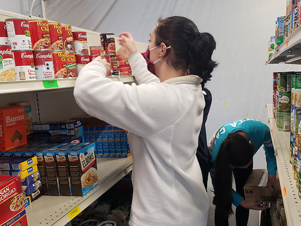 Student stocking shelves in Lion's Pantry