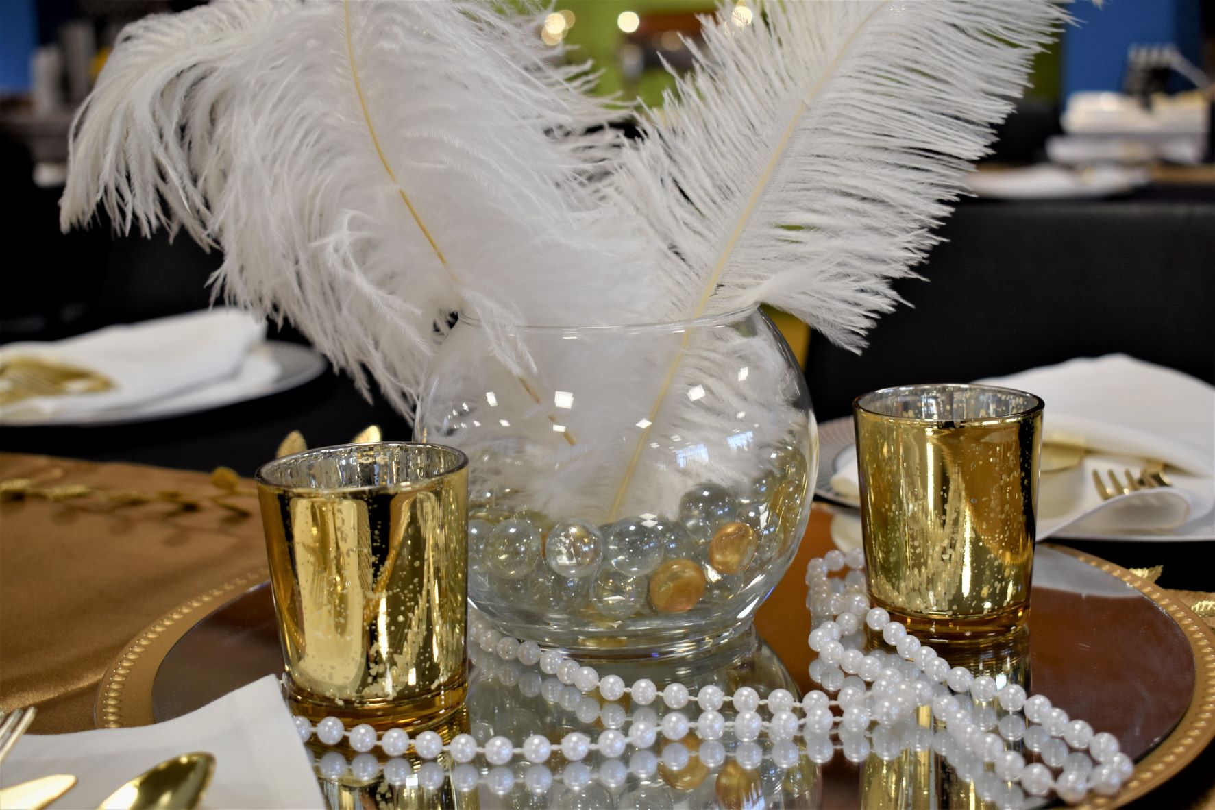 Centerpiece at old Hollywood event with feathers, candles, and pearls