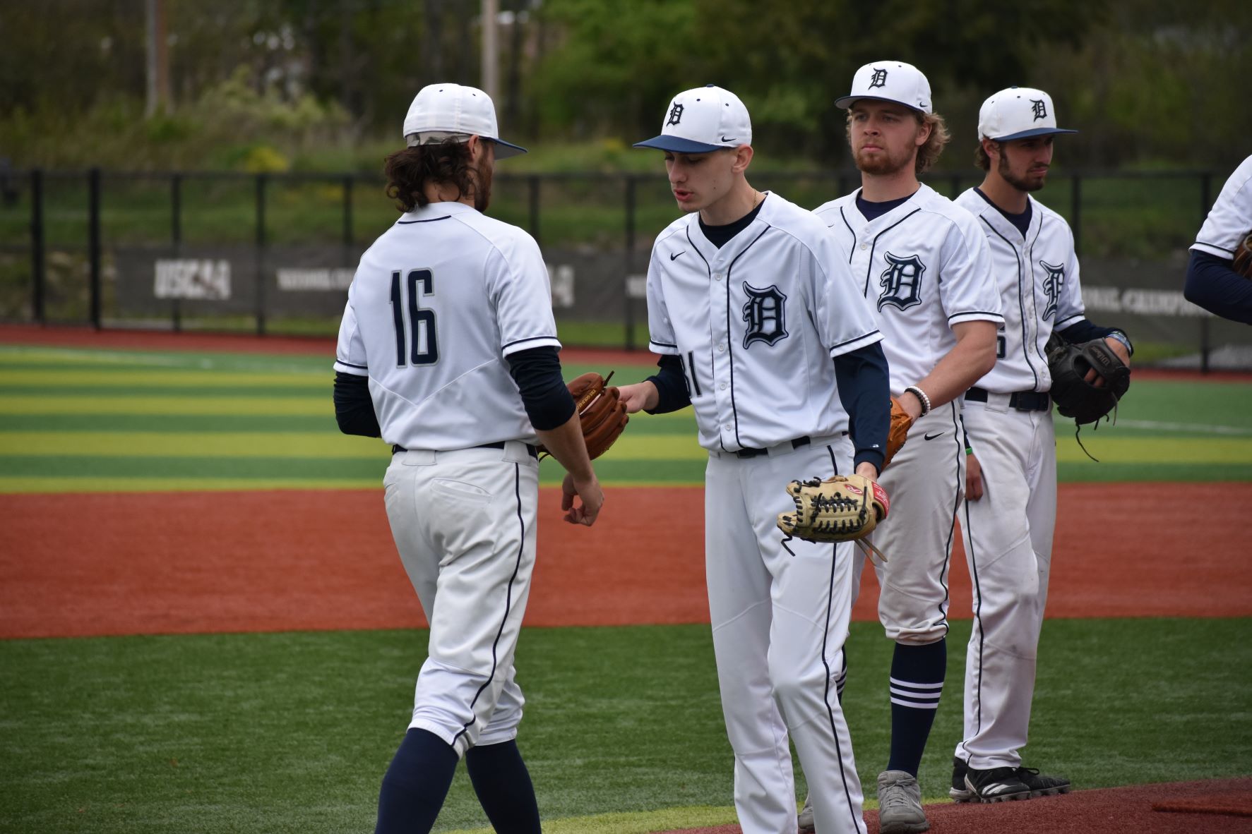 Pitching change in a baseball game, exiting pitcher hands ball to incoming pitcher