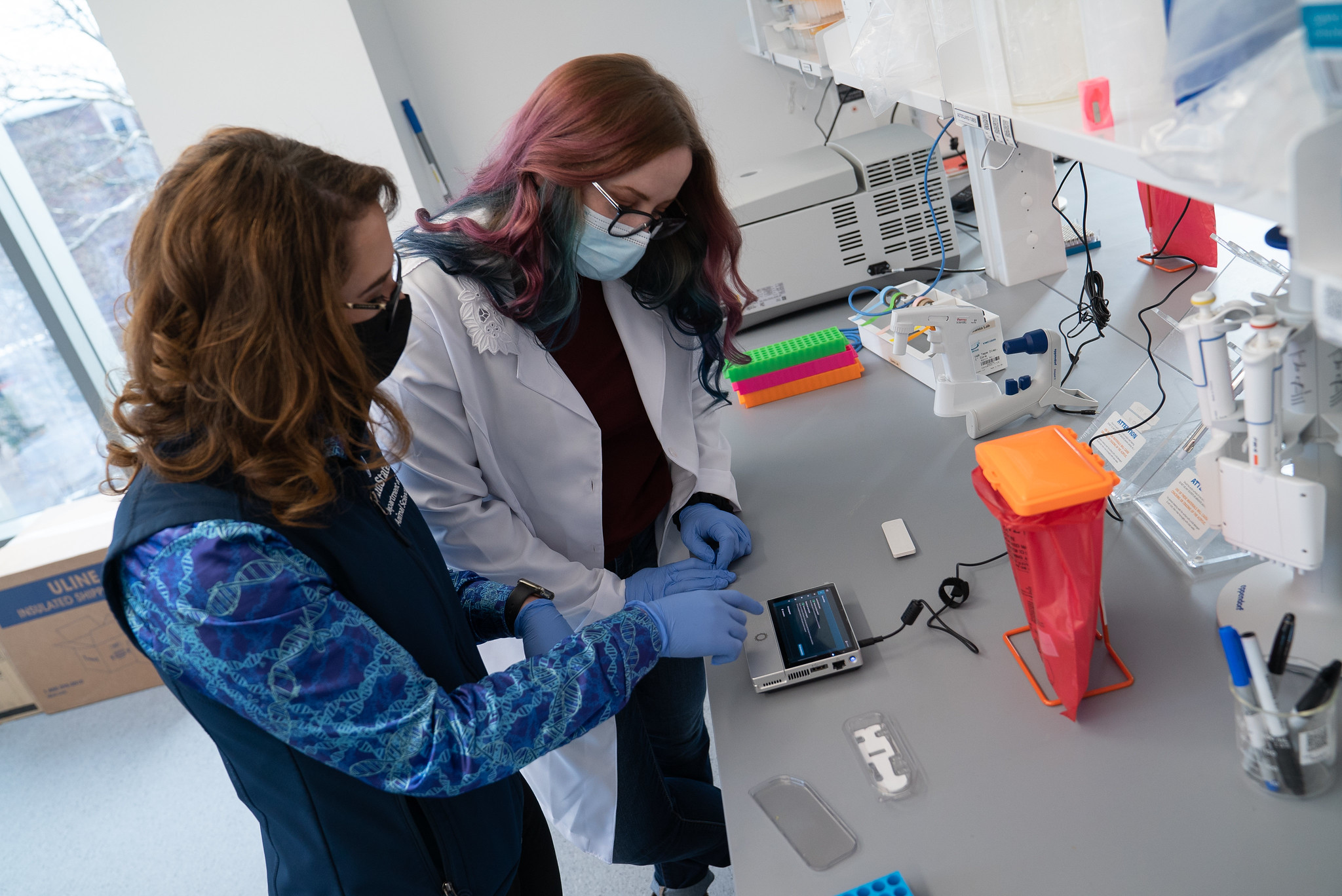 Assistant Professor of Food Animal Microbiomes Erika Ganda and graduate student Emily Van Syoc working at a lab bench