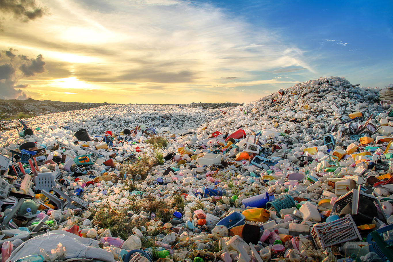 Mountain of plastic waste with sun shining.