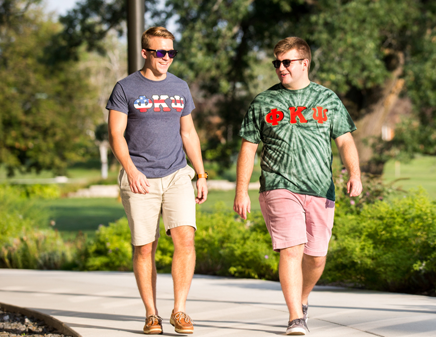 Two students walking wearing Phi Kappa Psi Fraternity shirts