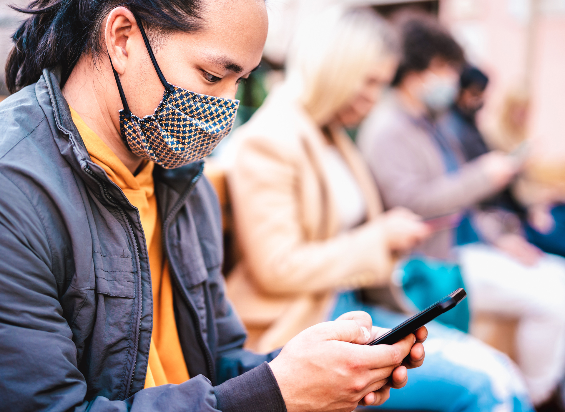 Man in mask looking at a smartphone