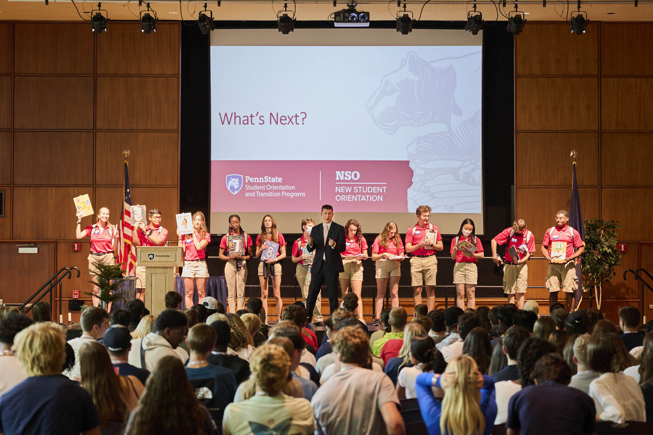 Orientation Leaders and NSO staff presenting on stage in Alumni Hall, with the audience facing away in the foreground