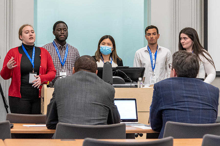 Students standing behind podium in front of classroom