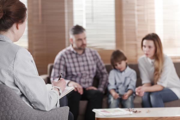 Rear view of female psychologist helping young family solve child behavorial problems. 