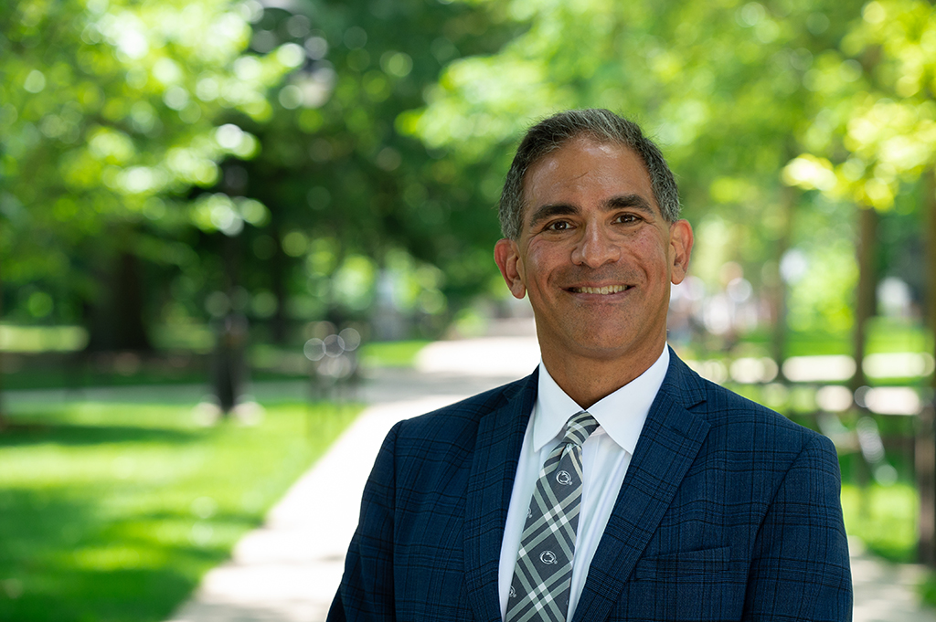 Justin Schwartz stands outdoors with green trees in background.