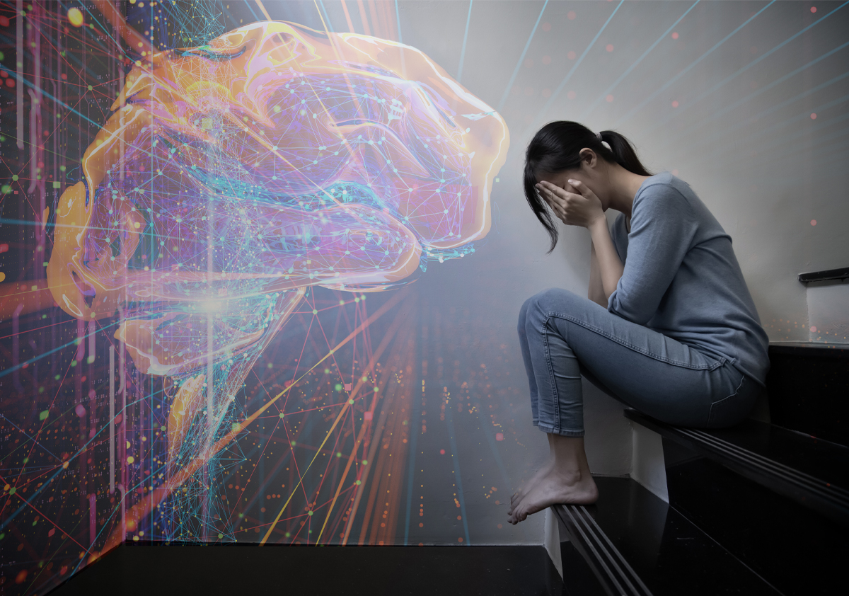 On the right side of the image, a person sits on a step with her face in her hands. A digital rendering of a brain is projected on the left side of the image. 