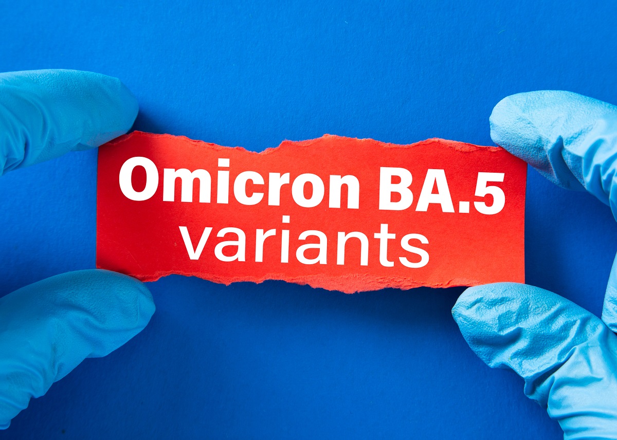 Doctor's hands in blue gloves hold writing on torn paper that says “Omicron BA.5 variants.”