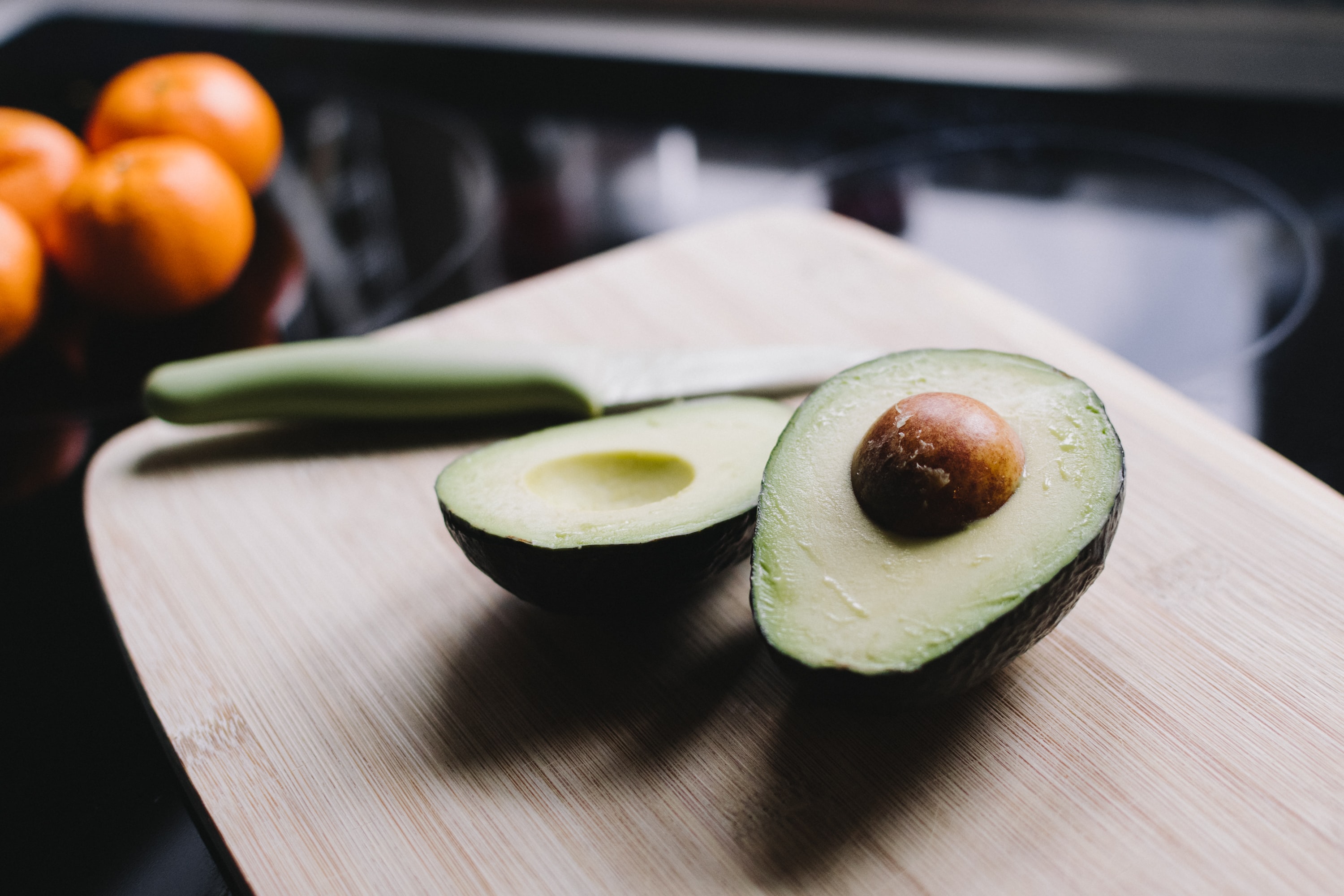 An avocado cut in half and lying on a cutting board