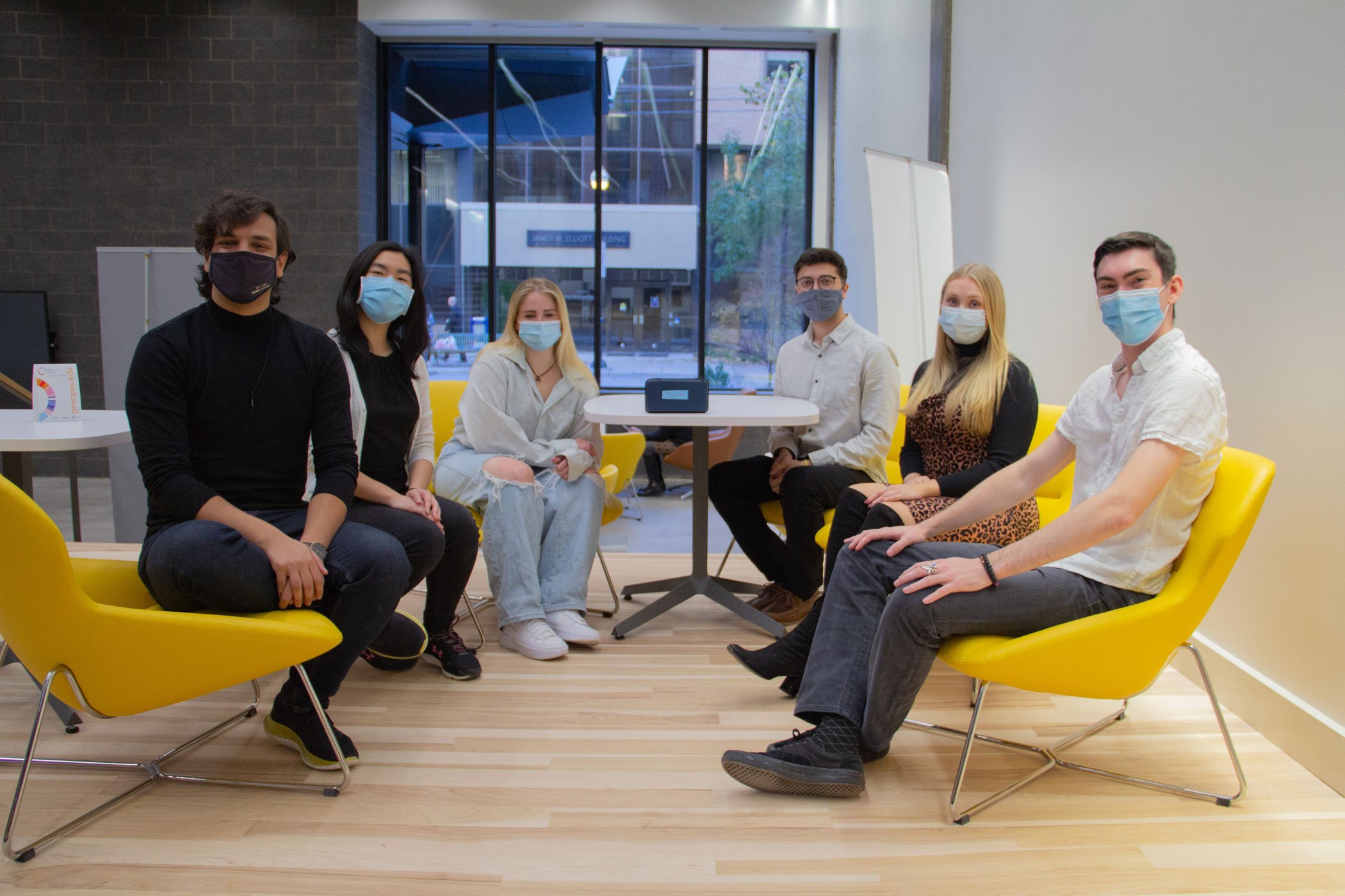 students sit in yellow chairs in office