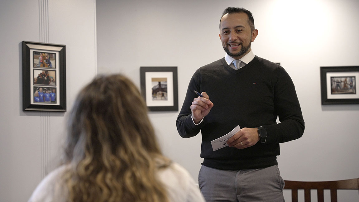 An admissions counselor standing with pen and paper in front of a student