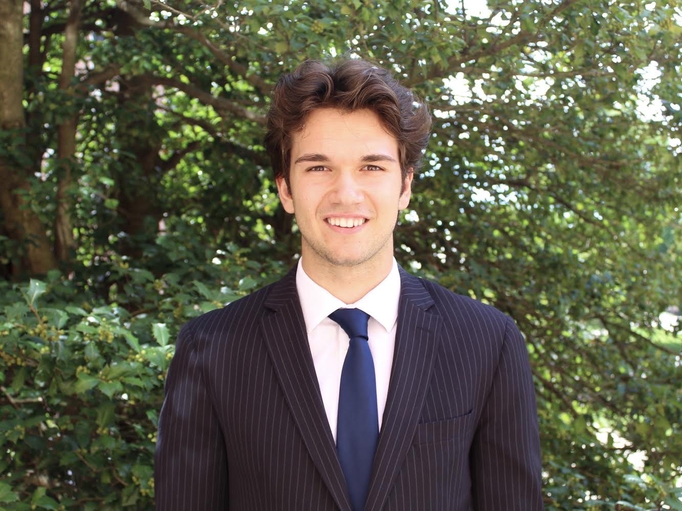 Benjamin Burlovic stands in front of trees and smiles at the camera