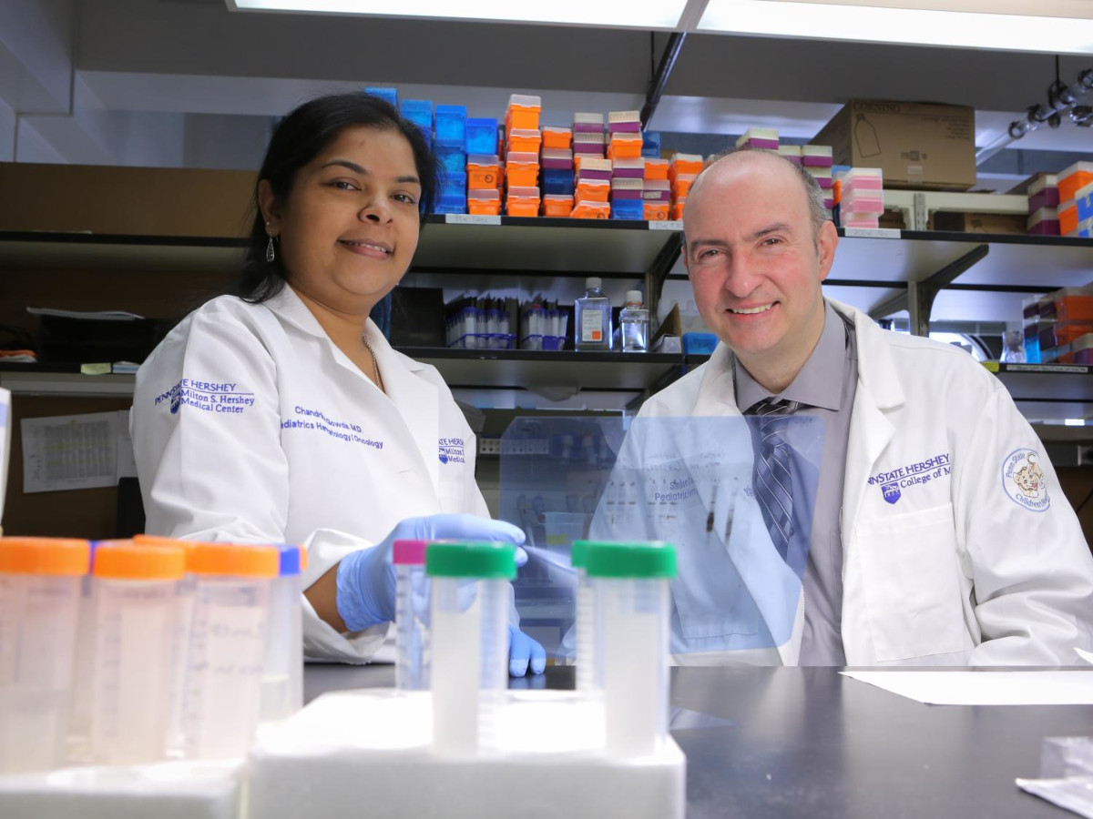 Two doctors wearing white coats are in a research lab