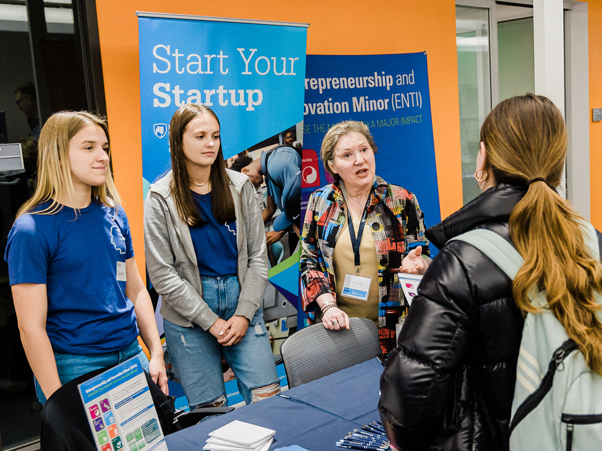 Students and Anne Hoag stand around ENTI information table set up at Happy Valley LaunchBox powered by PNC Bank